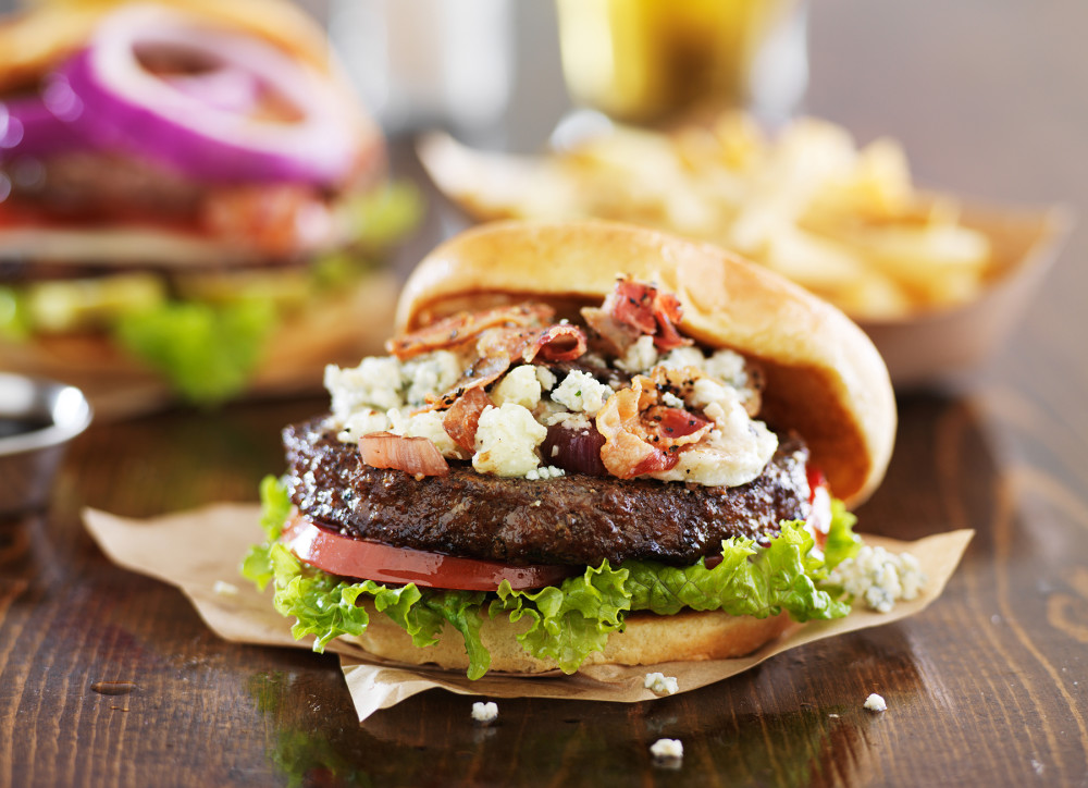 gourmet burgers on wooden table with bleu cheese and bacon